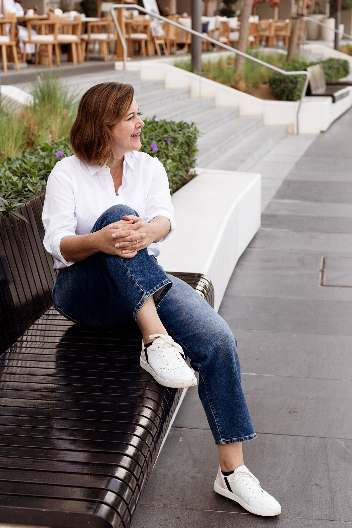 Ilse Vonk, fractional CEO, sitting relaxed on a bench in a modern outdoor setting.