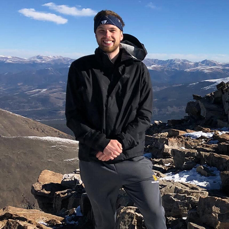 Before image of client standing on a mountain top in outdoor gear, smiling at the camera before professional Twin Cities dating photography session by Shannon Kathleen Photography.