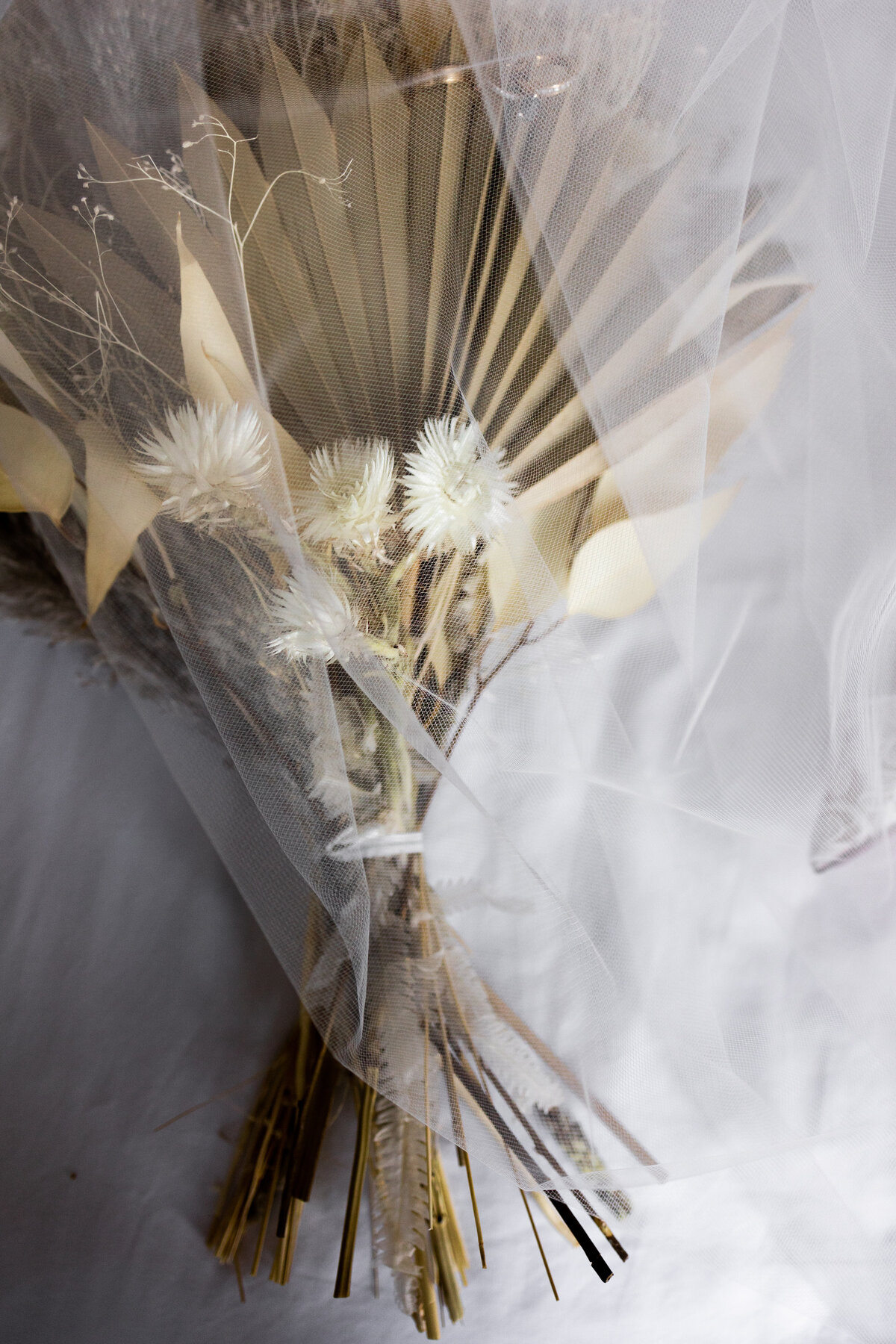 This image captures the essence of bohemian elegance with a stunningly arranged boho-style wedding bouquet. Featuring an eclectic mix of wildflowers, pampas grass, and delicate greenery, the bouquet radiates a whimsical, free-spirited vibe. Soft, natural light enhances the subtle colors and textures, making it a perfect inspiration for brides planning a boho-themed wedding. This photograph is an ideal showcase for florists and wedding planners aiming to promote unique, trend-setting floral arrangements.