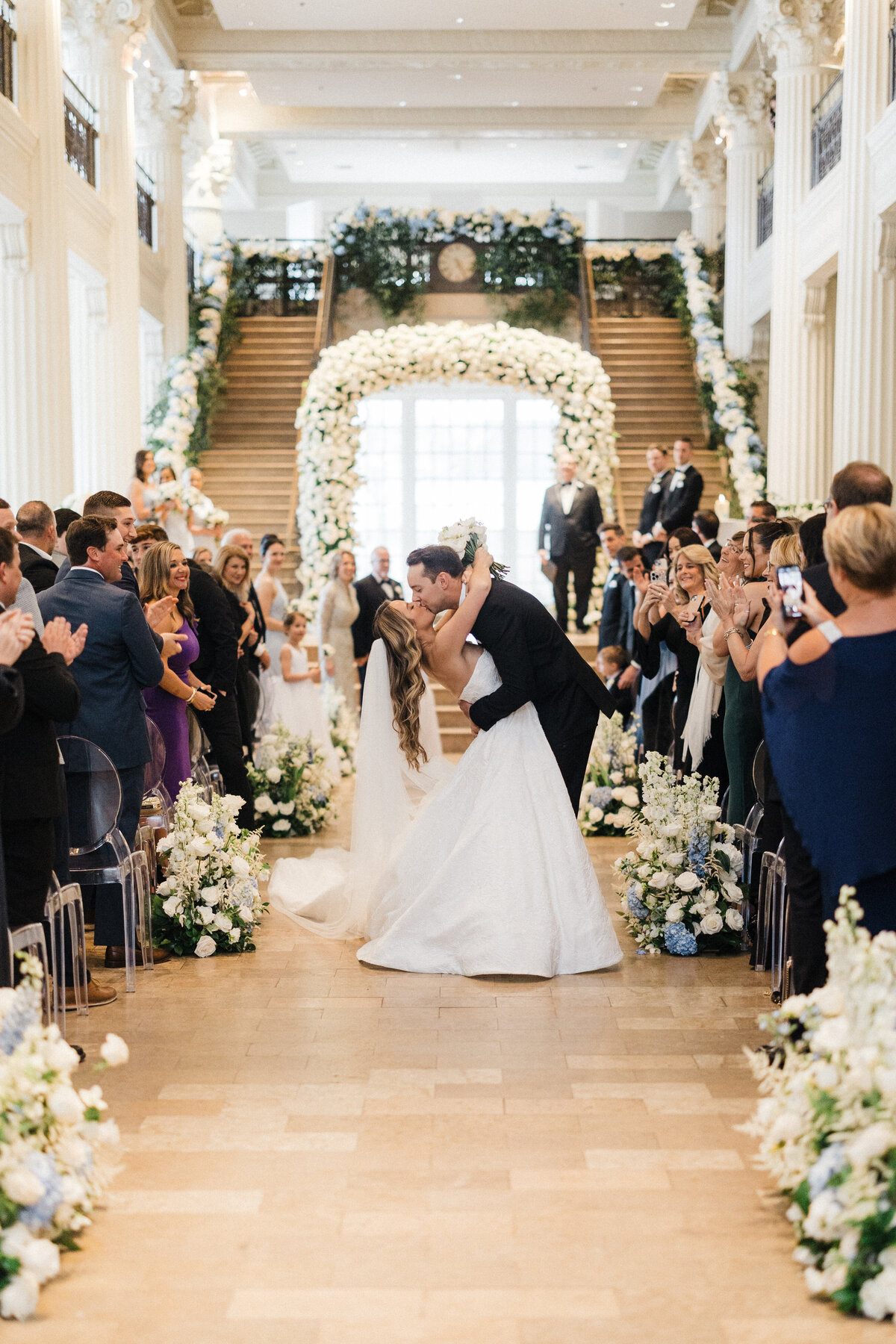 Bride and groom kissing in the middle of the aisle while guests cheer