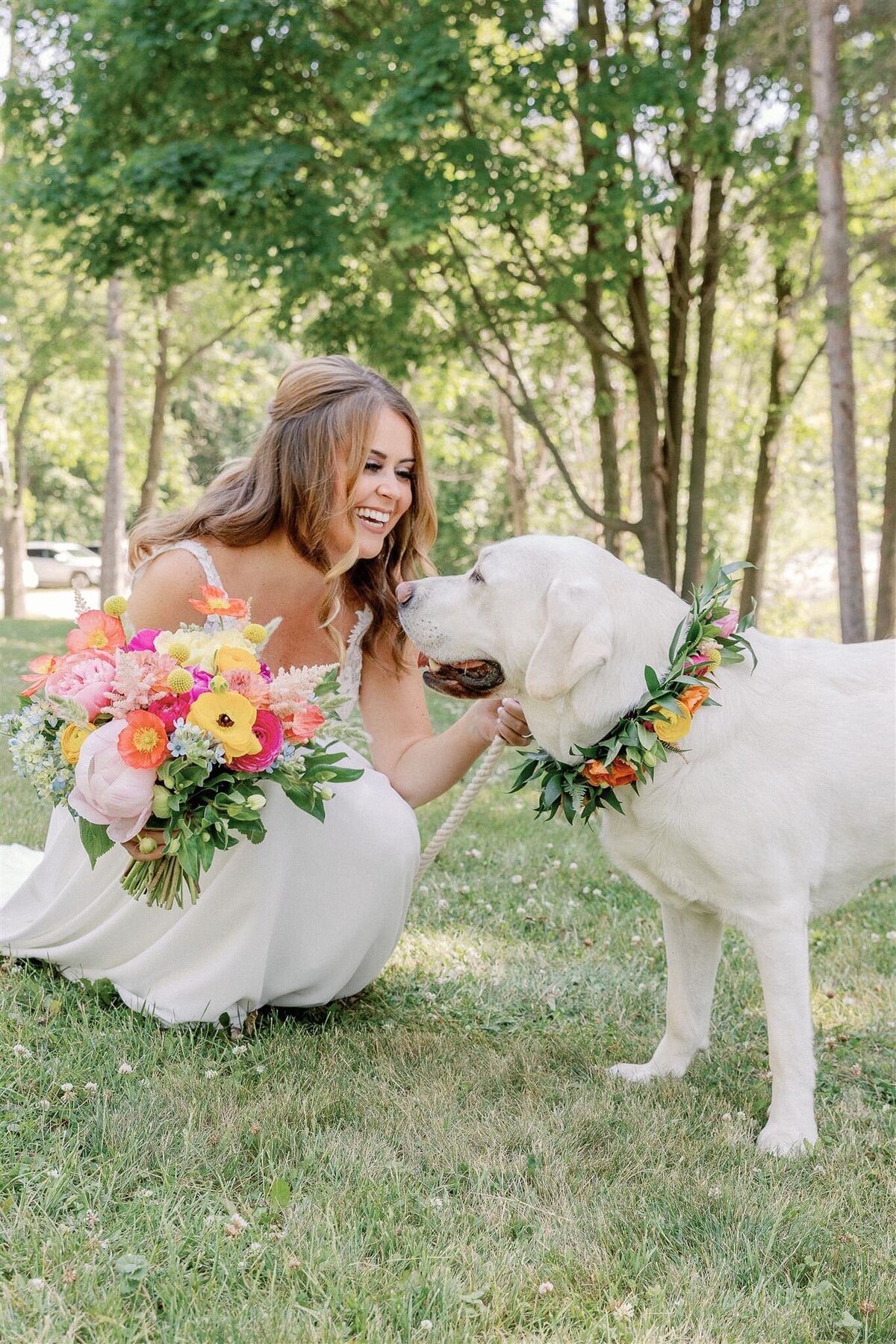 A photo of a bride smiling at her yellow lab on her wedding day