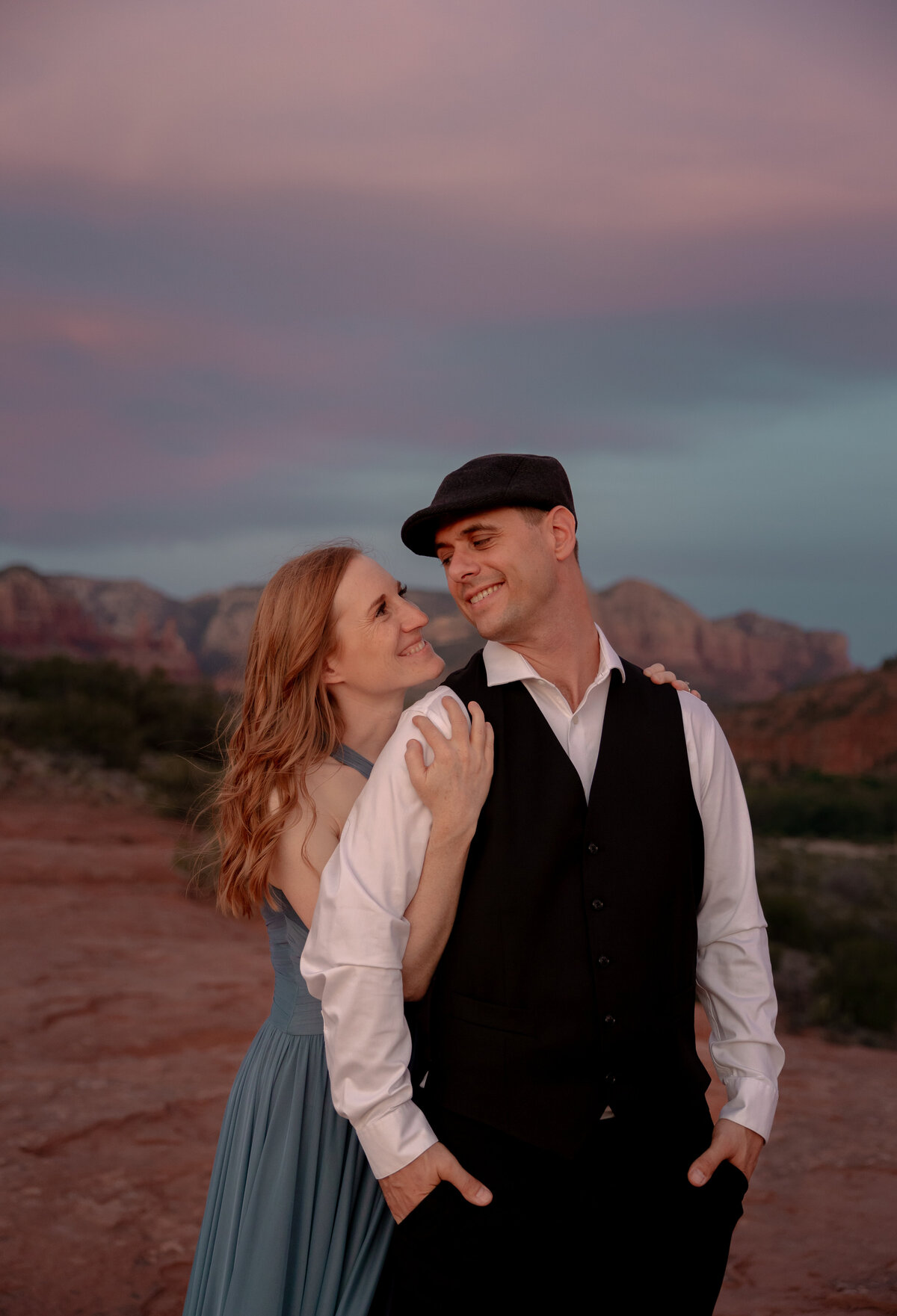 Couple standing against red rock backdrop during Sedona engagement session