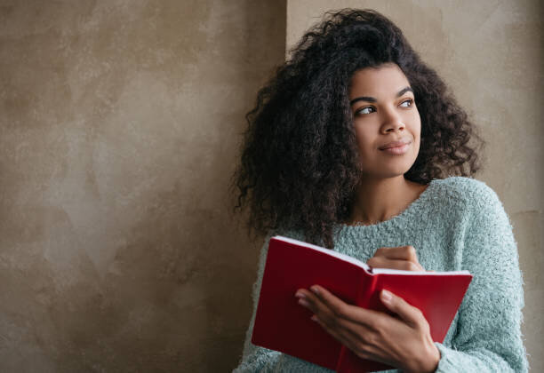 Afro textured hair woman with book in hand, looking away