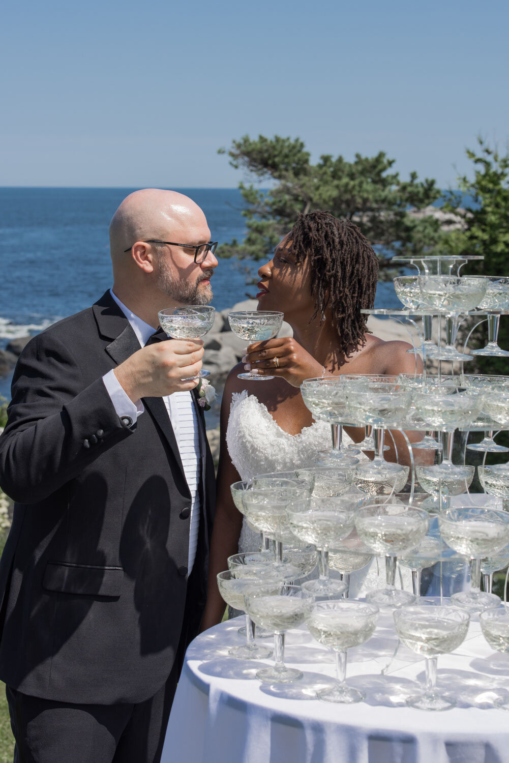 Bride and groom drinking champagne in front of their champagne tower