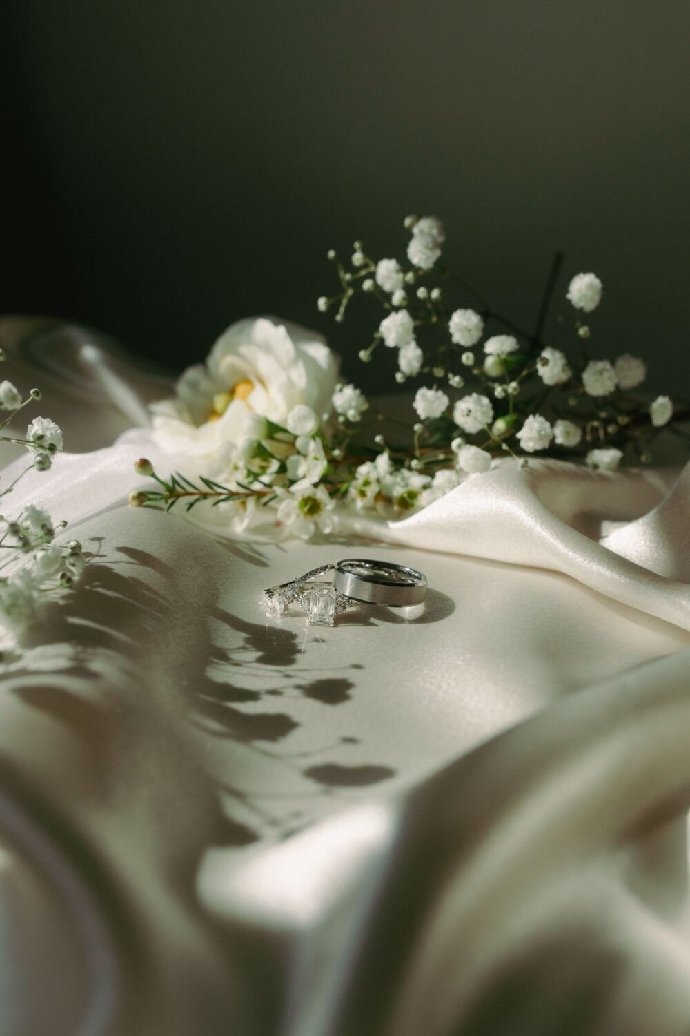 Bride and groom rings on silk fabric with floral shadows with film editing