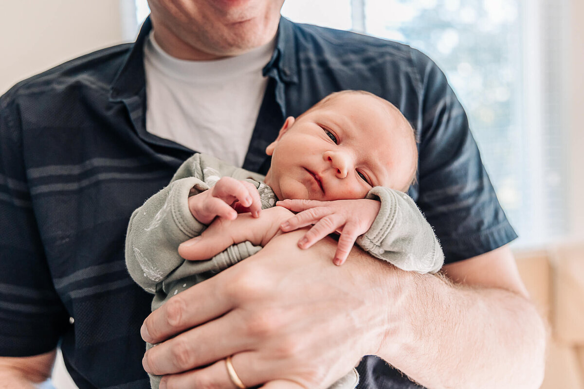 Baby holding onto dads hand as he holds him