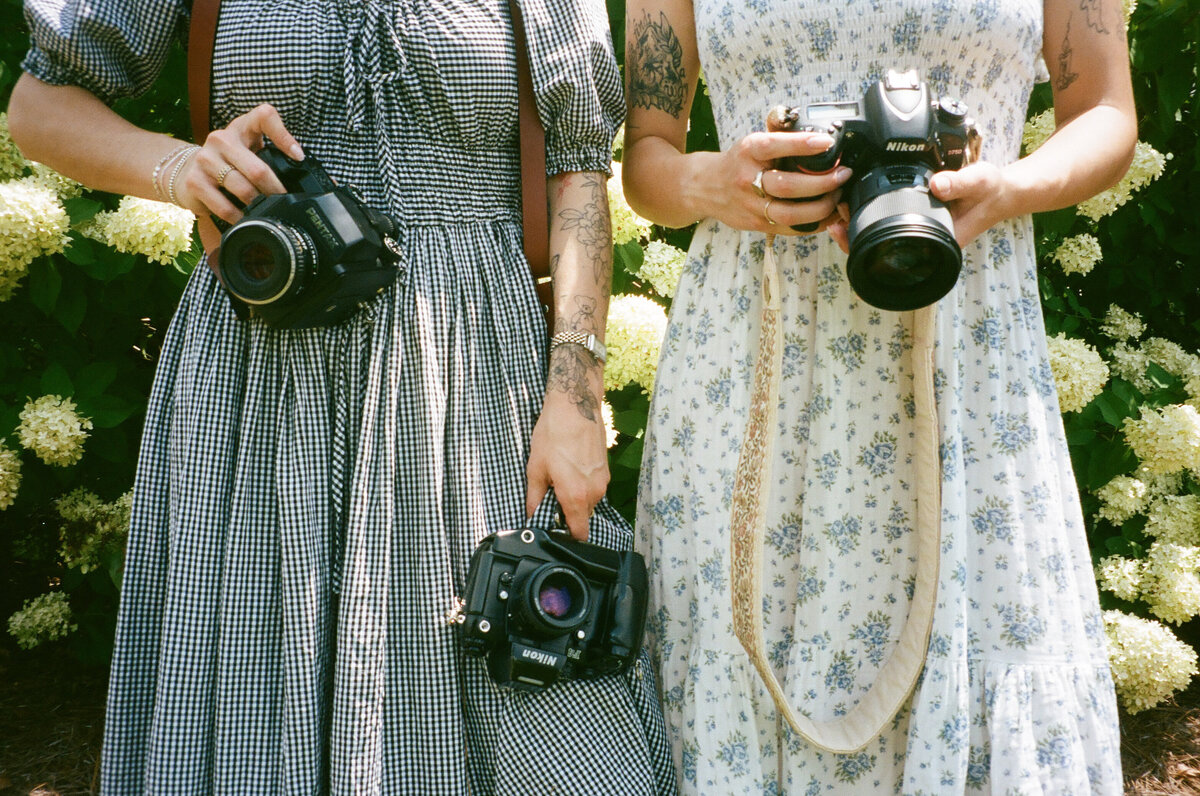 huntsville photographer holding cameras in front of hydrangea 
