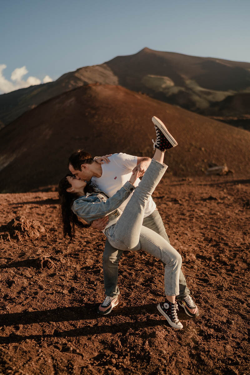Séance d’élopement en Sicile sur l’Etna, les amoureux dansent sur une terre rouge volcanique au coucher du soleil.