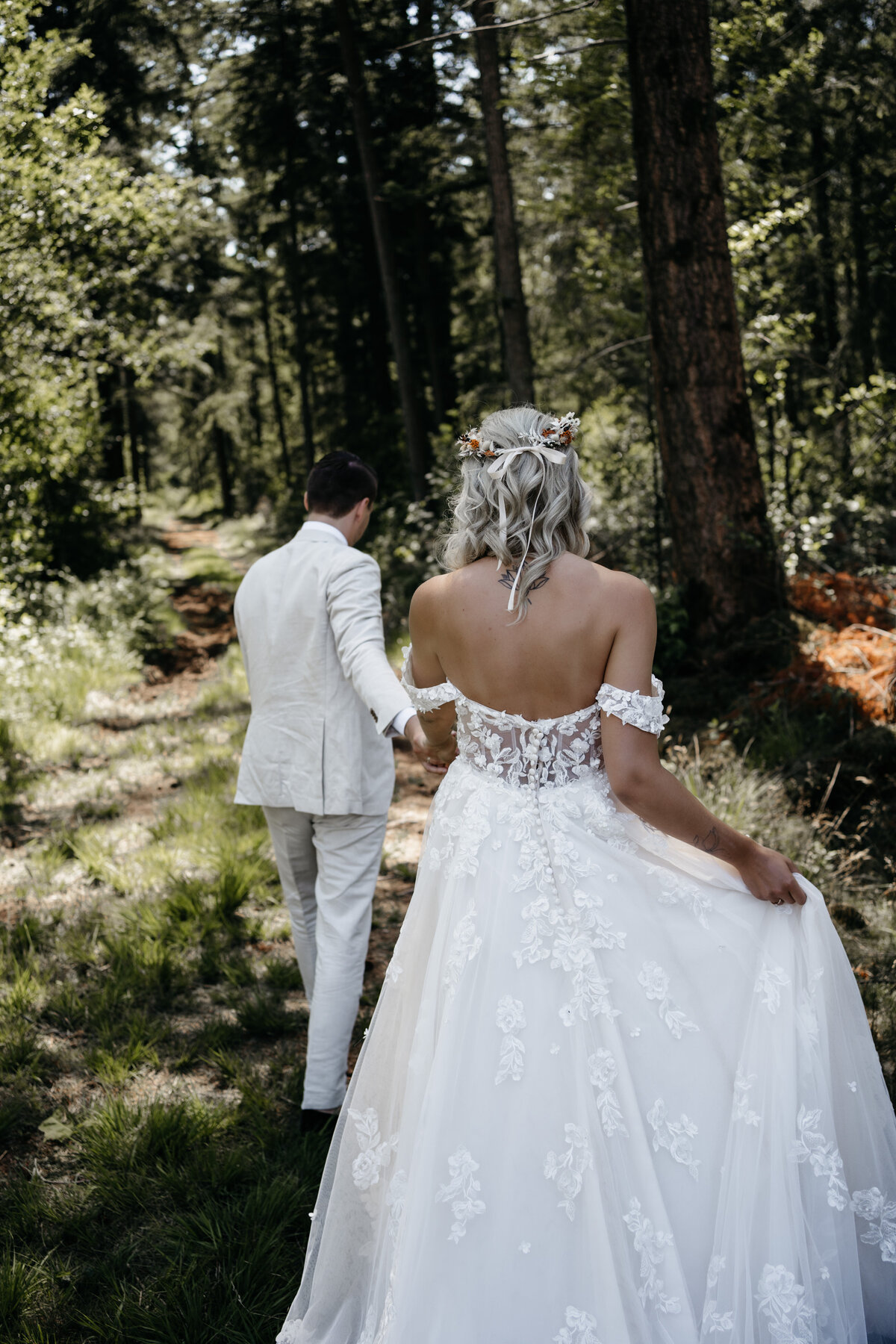 Bruidspaar loopt hand in hand tijdens de shoot in het bos. 