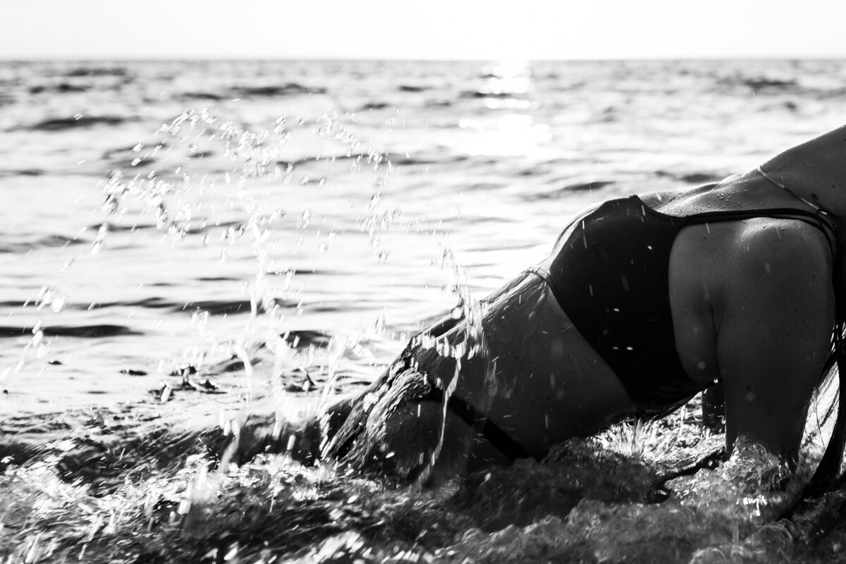 Bare silhouette of a woman against the backdrop of a golden sunset at the beach