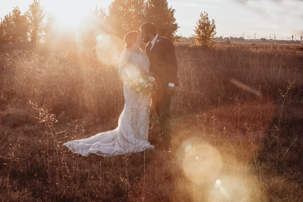 bride and groom in field at golden hour
