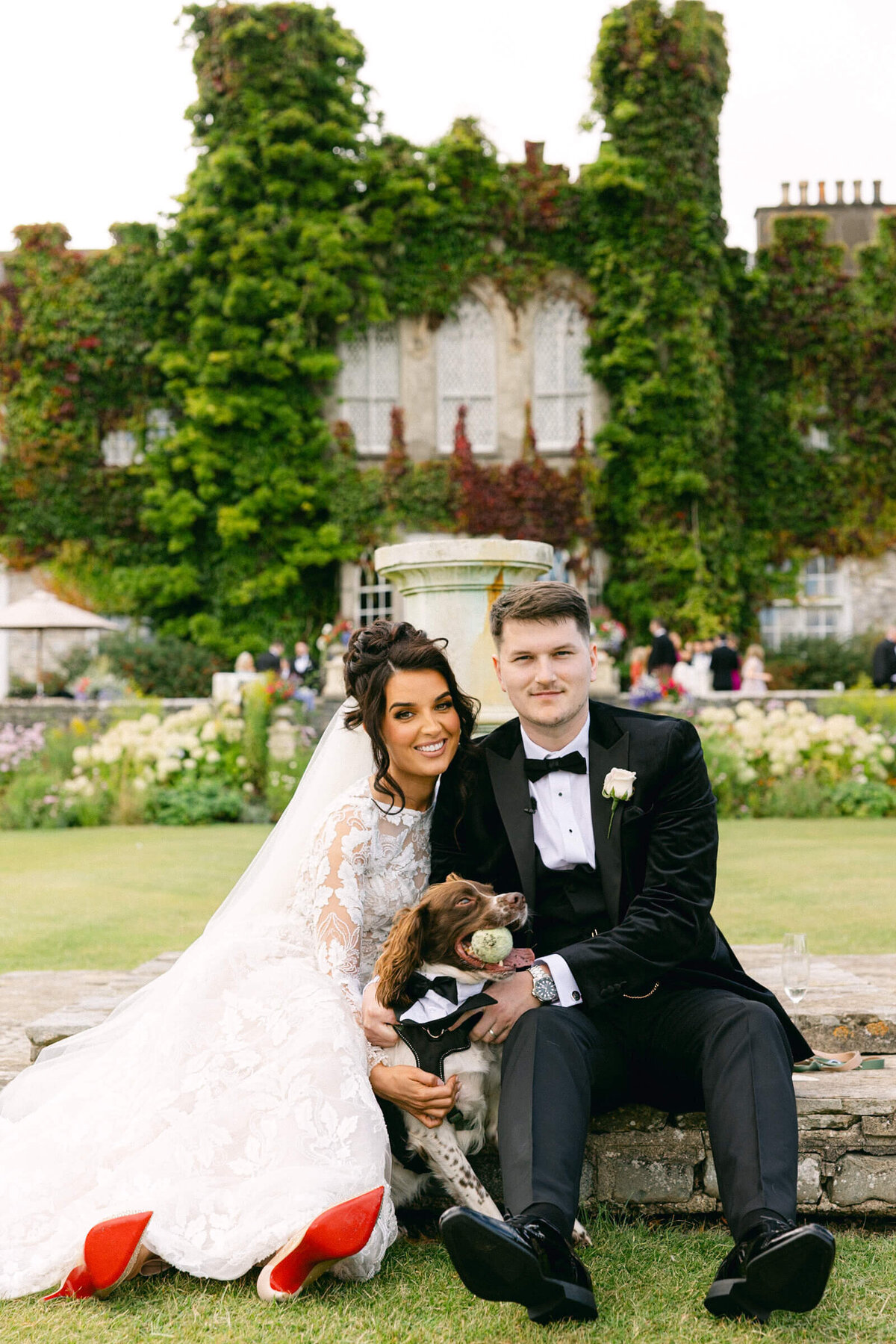 A wedding photo of the bride & groom and their dog with Luttrellstown Castle behind them
