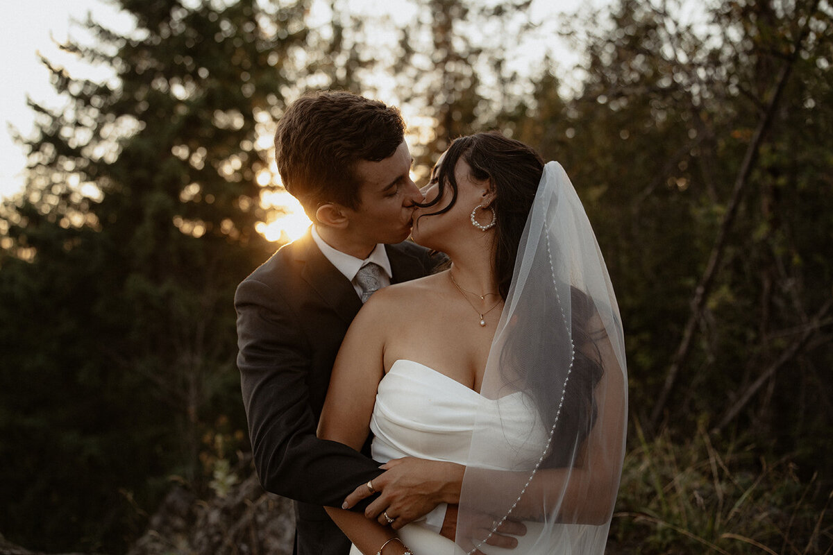 Couple kissing at sunset as the sun dips behind them at the Anglemont Inn