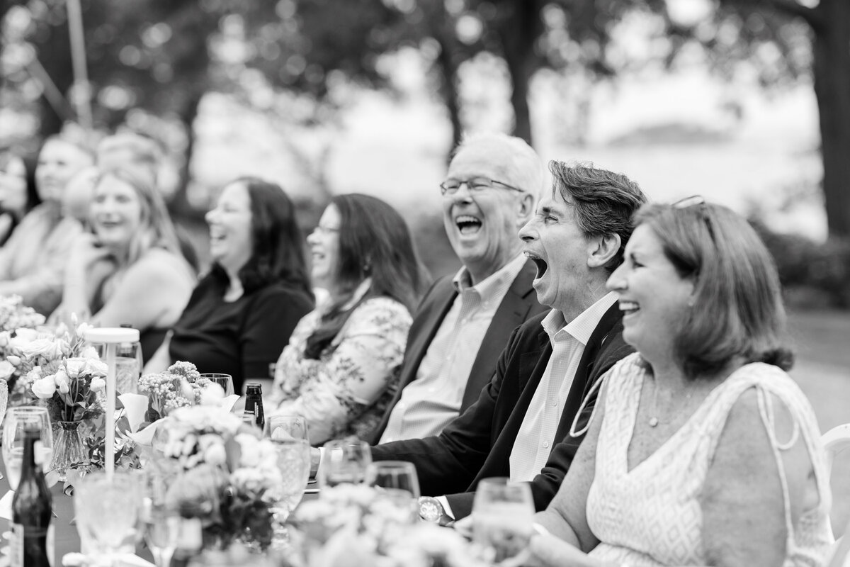 Guests laughing during rehearsal dinner speeches
