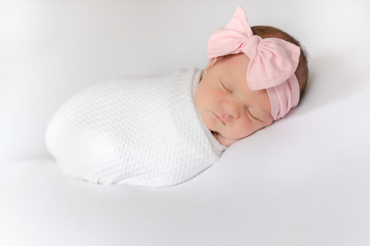 Newborn girl curled on her tummy in a home.