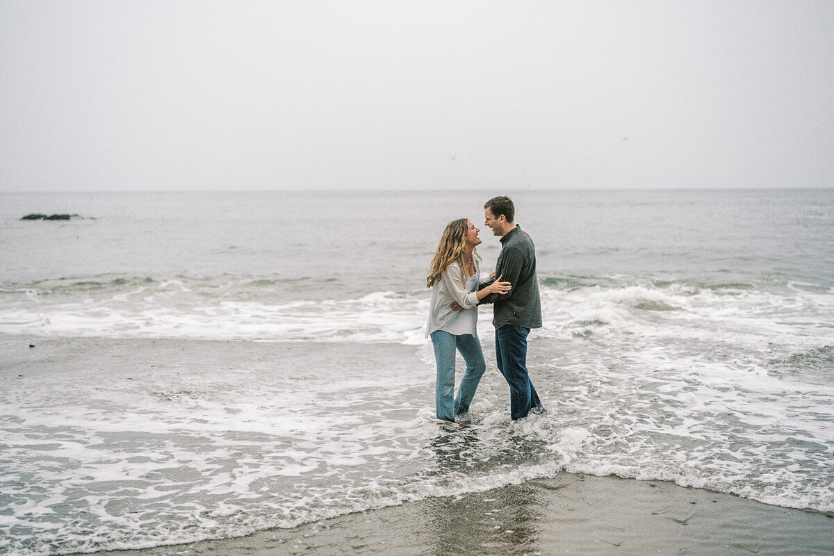 A couple playing in the waves on a misty day at the Oregon coast. 