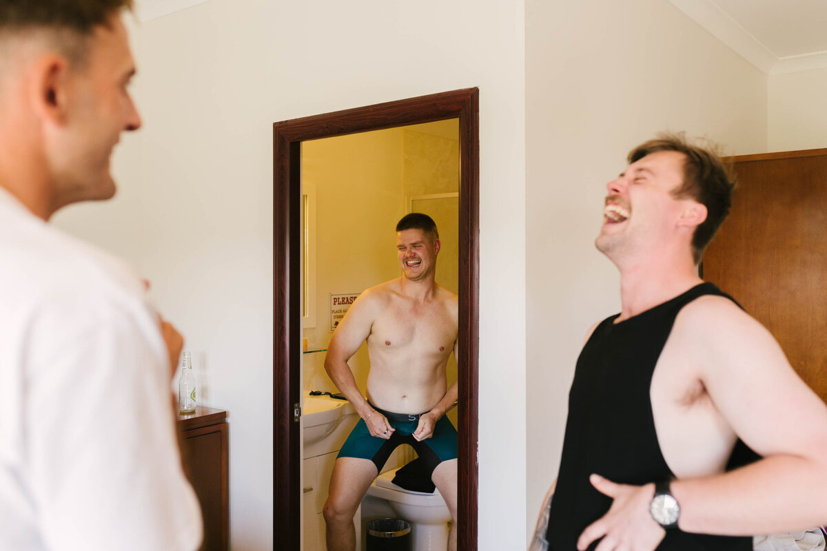 As one of the groomsmen grabs his crotch, the groom belts out in laughter. 