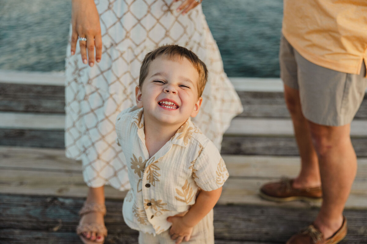 Close up of a child smiling brightly with parents behind them.