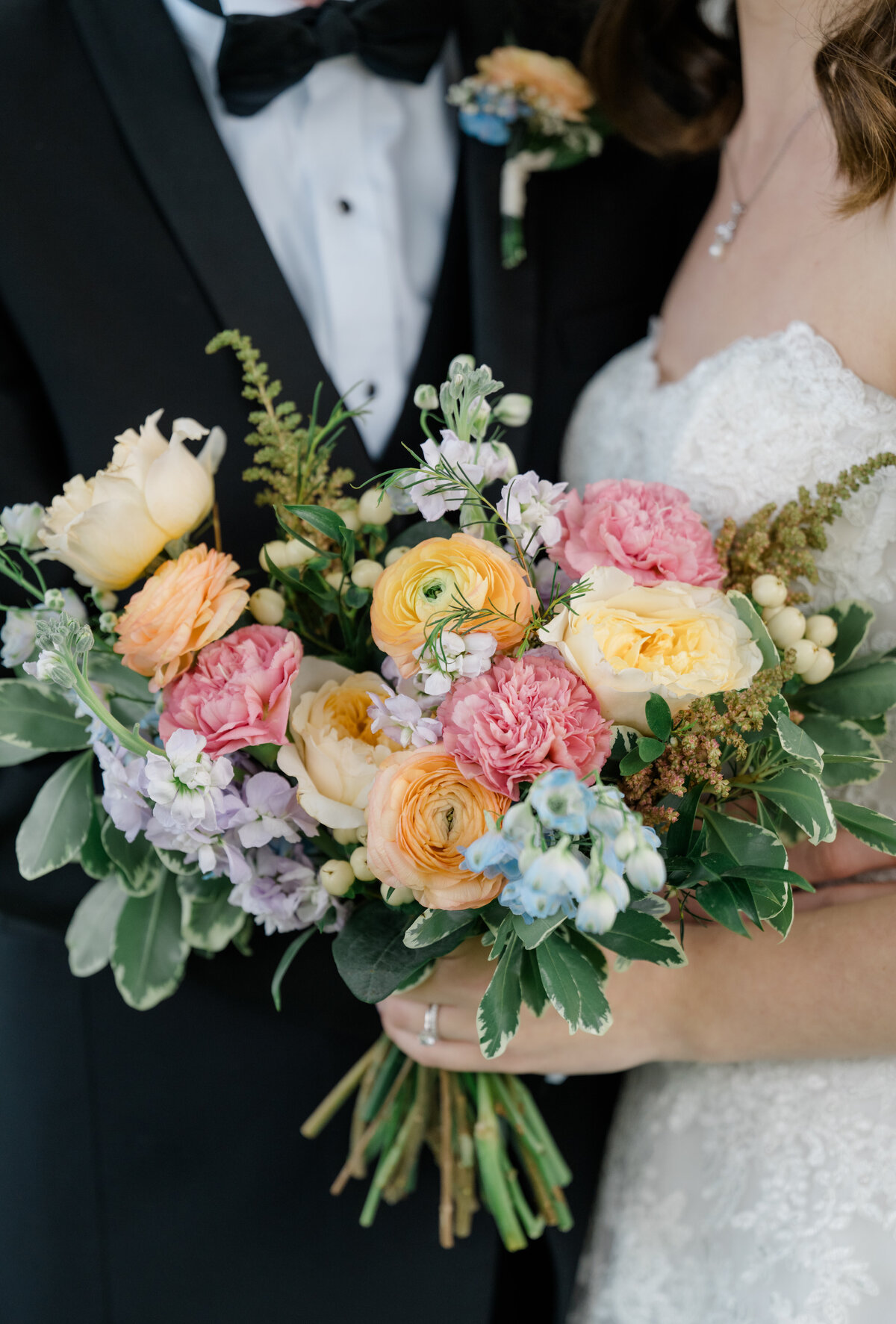 colorful wedding bouquet held by bride with her groom
