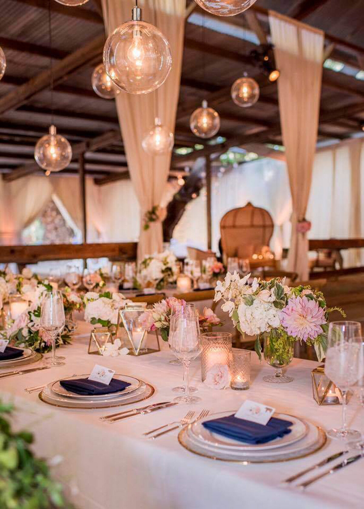 Elegant reception table set-up, with colorful floral centerpiece, glasses,  utensils, and plates