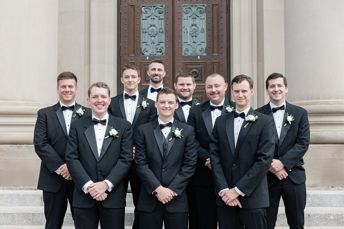 A groom and his groomsmen on the steps of Holy Cross