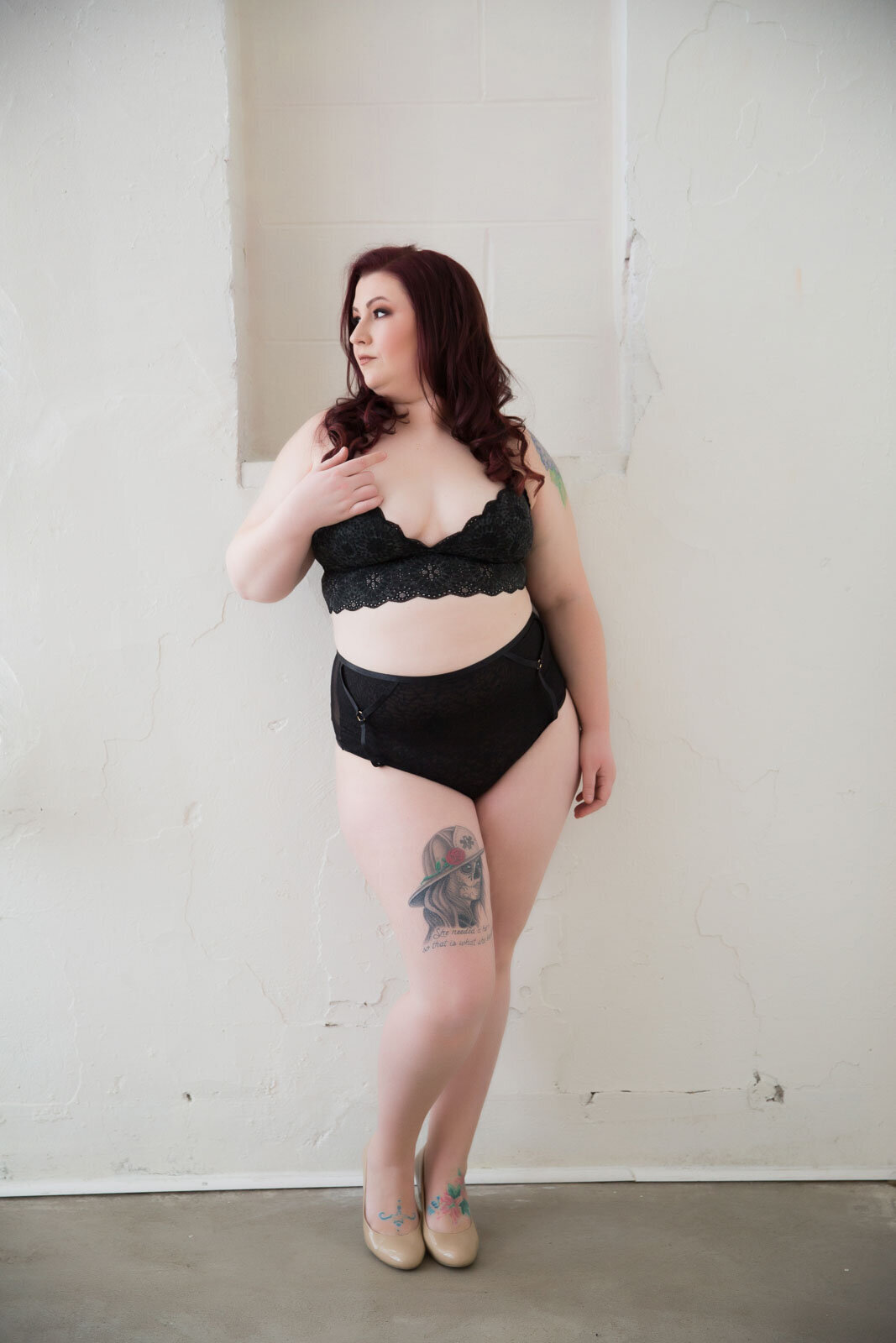 beautiful-plus-size-woman-in-black-lingerie-posing-in-front-of-a-white-wall