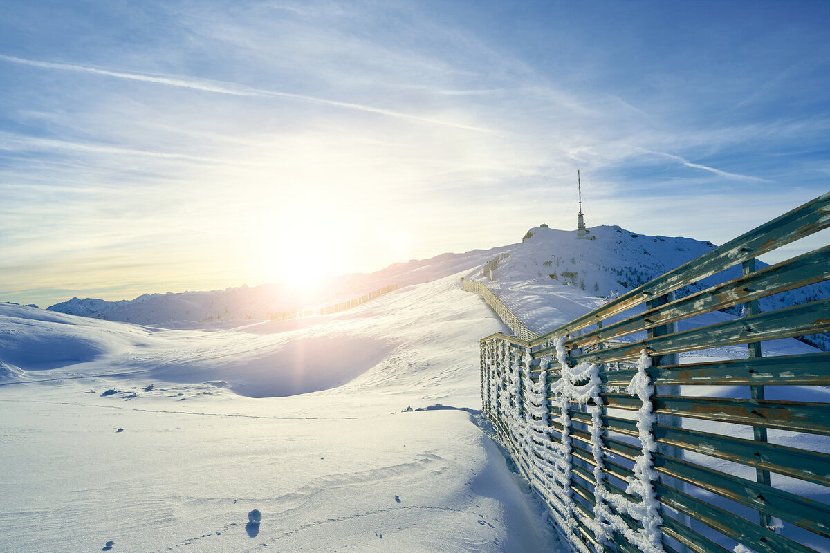 Sonnenaufgang über dem verschneiten Dobratsch-Gipfel mit markanten Schneefangzäunen – kraftvolle Winteraufnahme aus Kärnten vom Fotograf Atelier Schulte – Spezialist für stimmungsvolle Alpenfotografie.