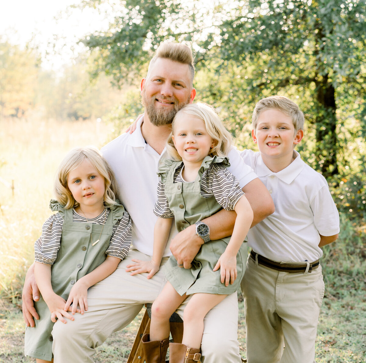 dad holding his daughters and his sone standing to the side at an outdoor Christmas Mini Session event