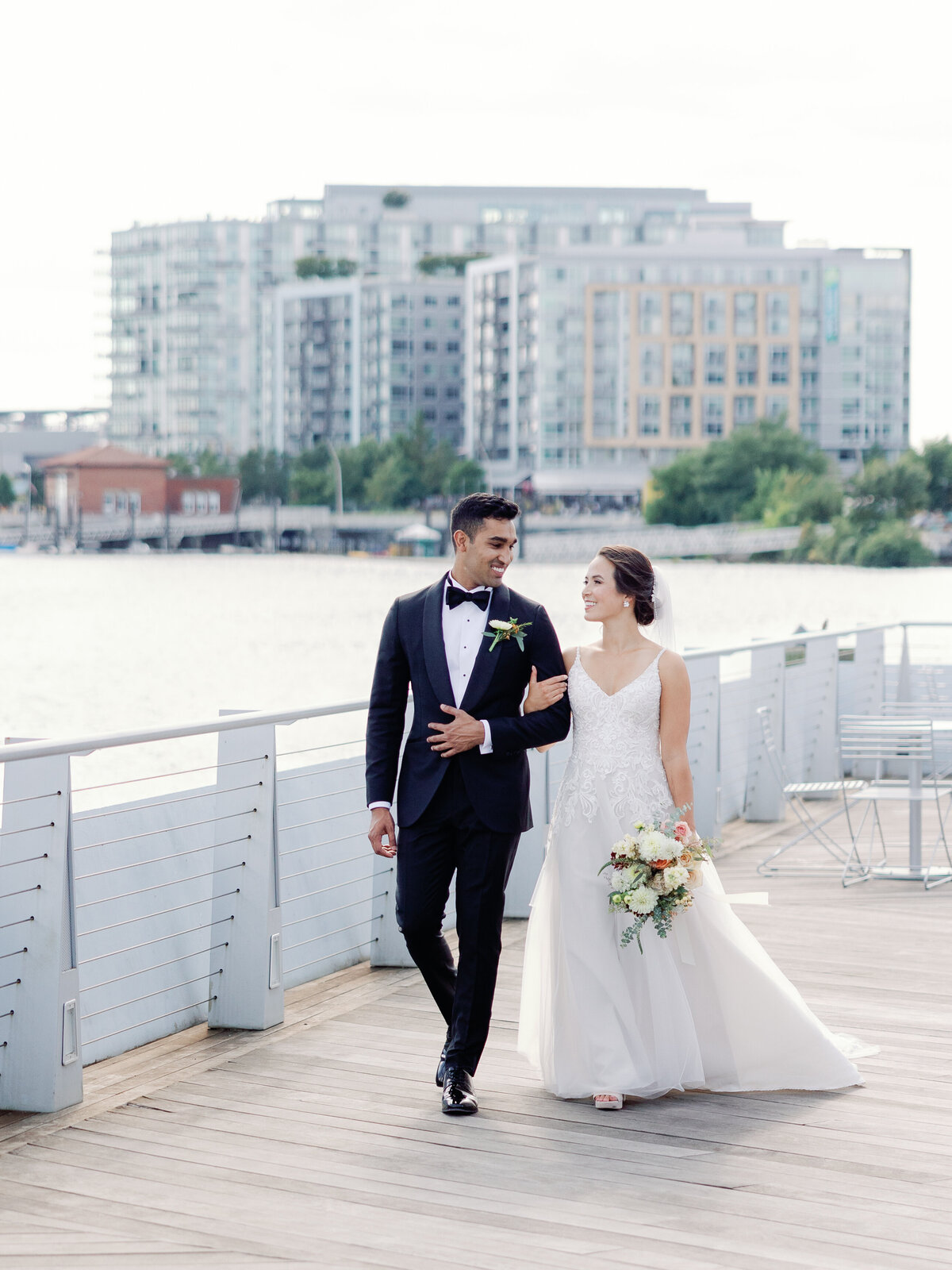 A bride and groom walk together down the dock at the wharf in washington dc