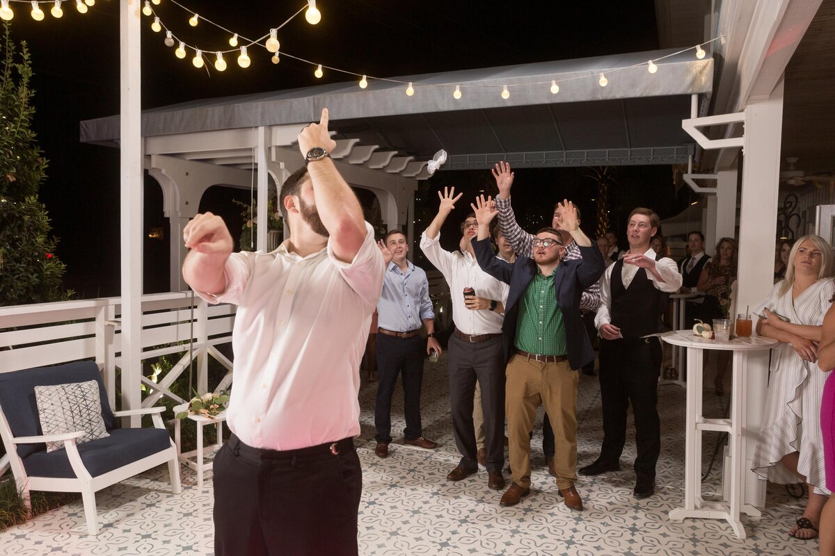 The groom tosses the garter to bachelors to see who will be married next.