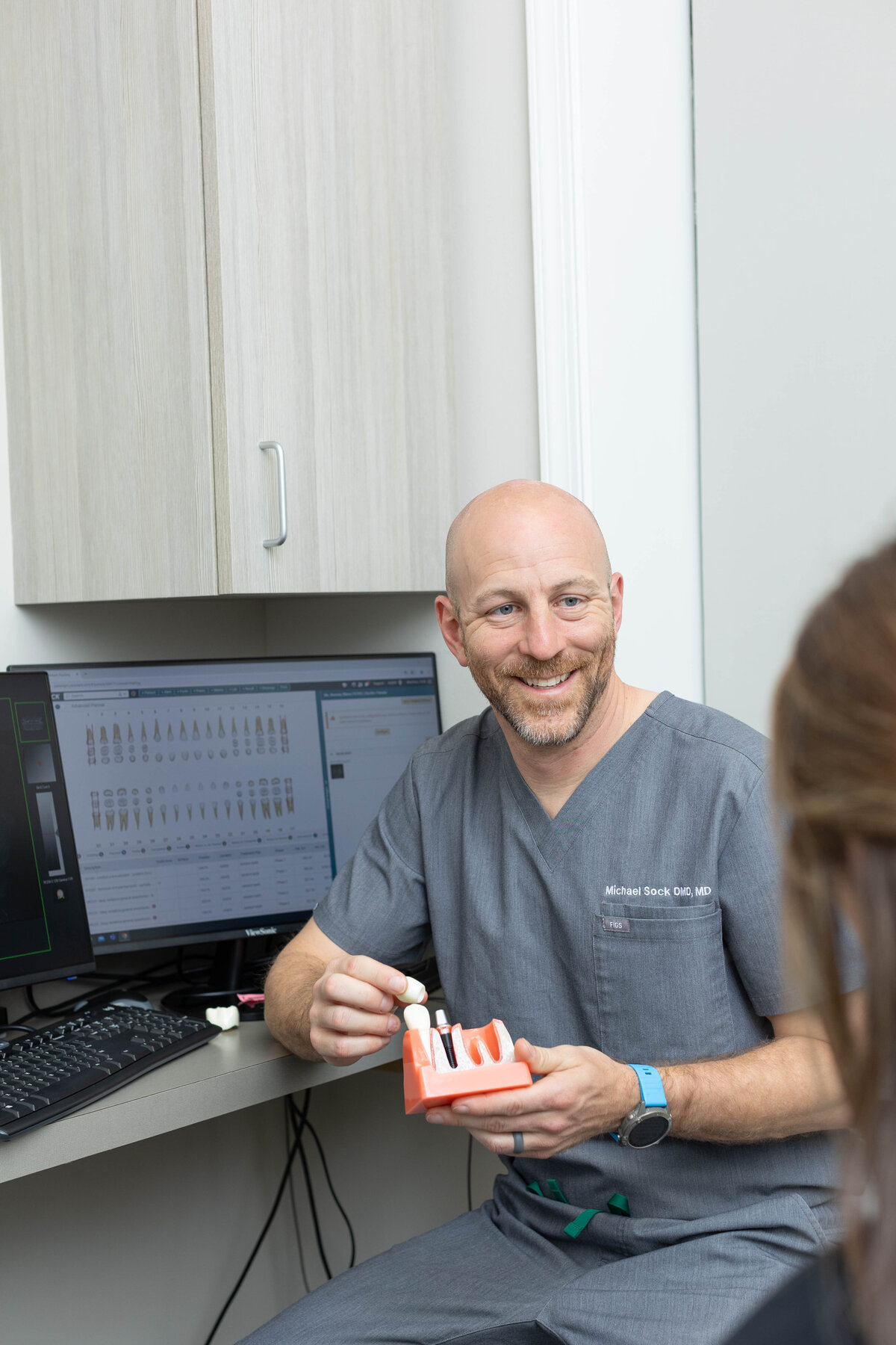 Dentist smiling at a patient showing a set of plastic teeth