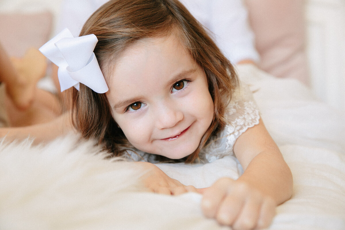 A small girl laying on a bed smiling