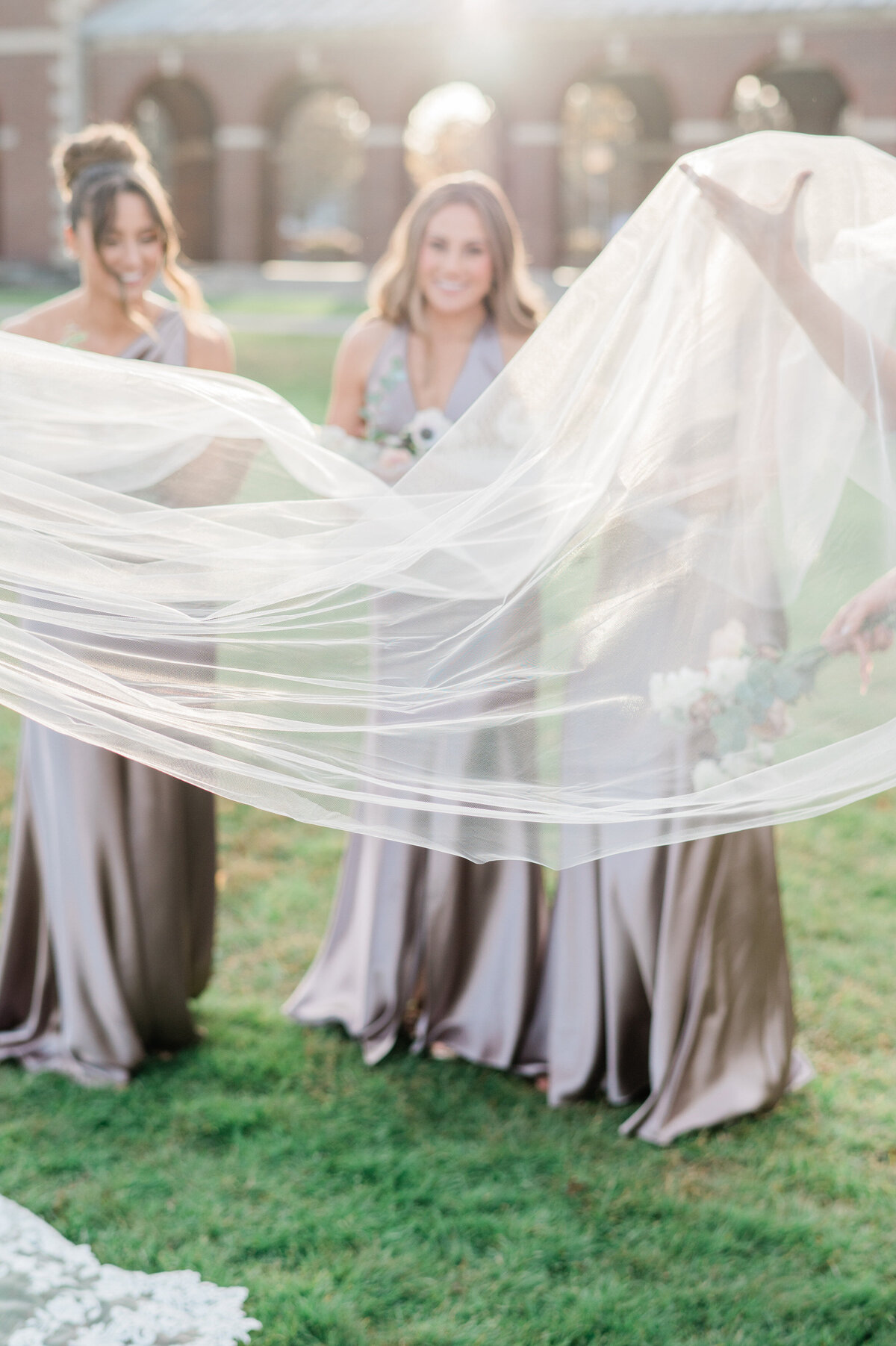 Veil blows in the wind beside three bridesmaids 