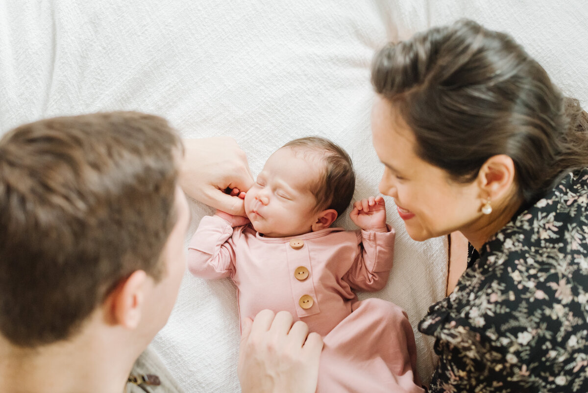 Parents looking at newborn in pink onesie - Washington DC Newborn Photographer