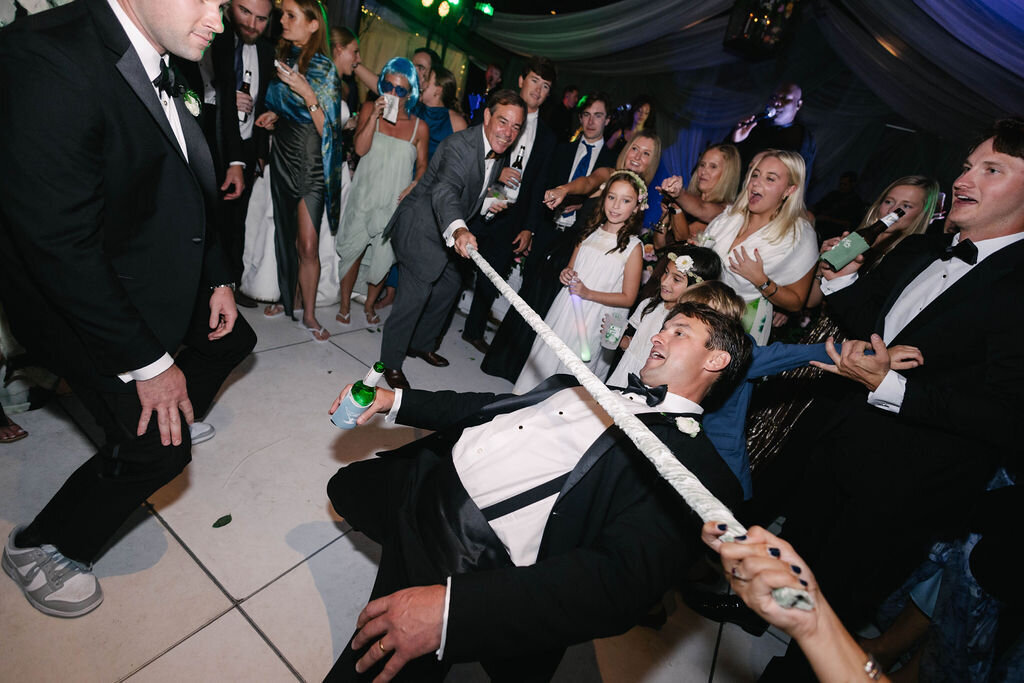 Groom doing the limbo surrounded by cheering guests on the dance floor during a fun wedding reception at The Bascom in Highlands, NC.