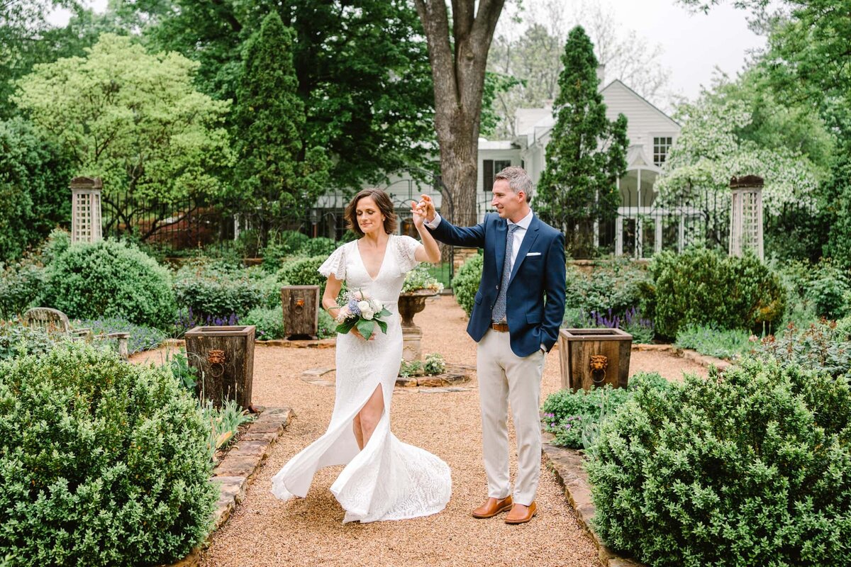 Groom twirling bride holding bouquet in Waterperry Farm garden wedding