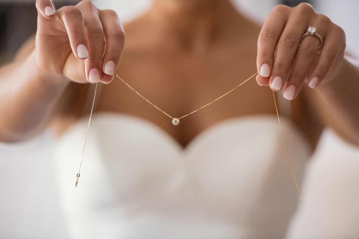 bride holding her necklace for wedding at The Muttontown Club