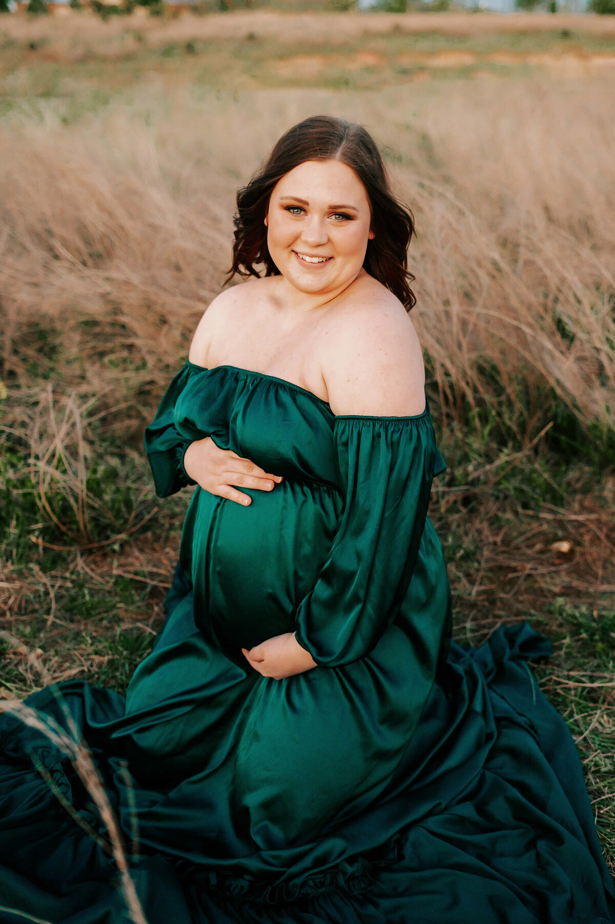 maternity photographer The XO Photography captures pregnant mom kneeling in field in Branson