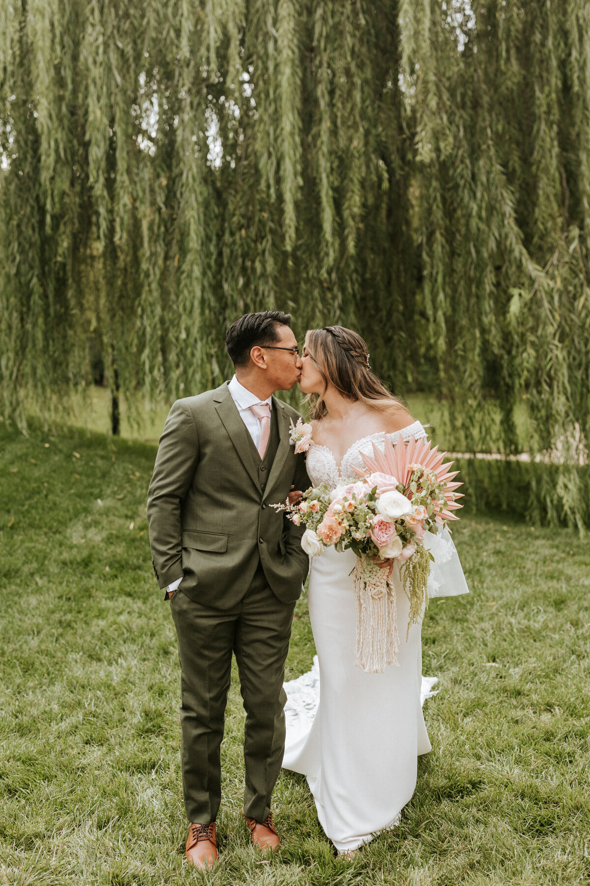 newlywed couple kissing in front of willow tree