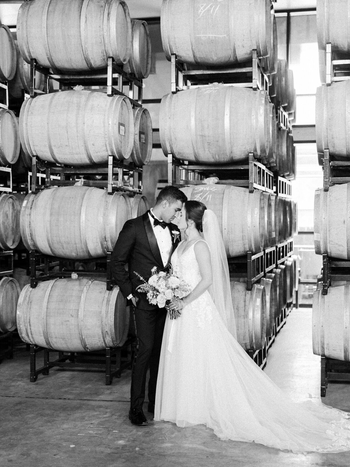 A bride and groom share a kiss in the wine cellar at district winery in washington dc