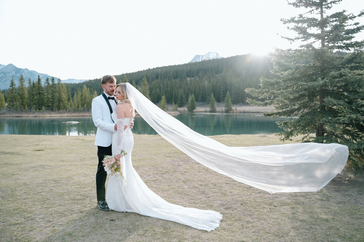 Bride and groom embrace at sunset near a mountain lake in Banff National Park.