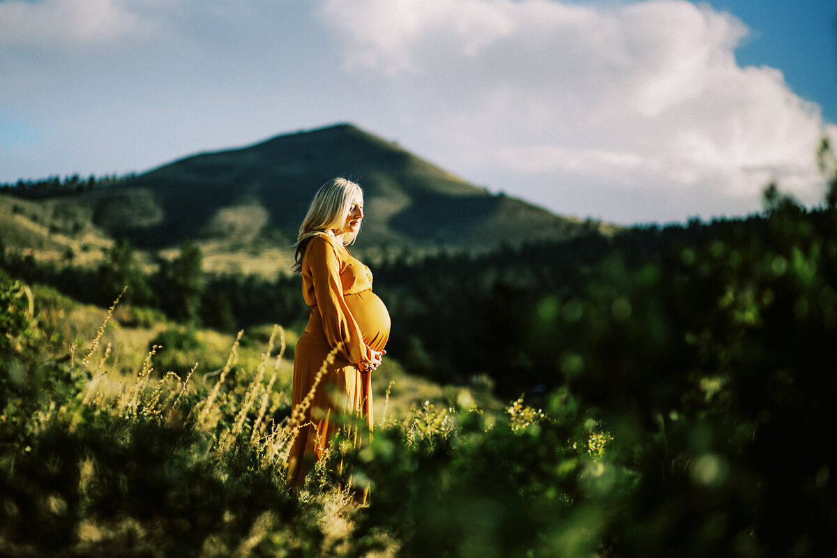 a woman in an orange dress stands in the mountains