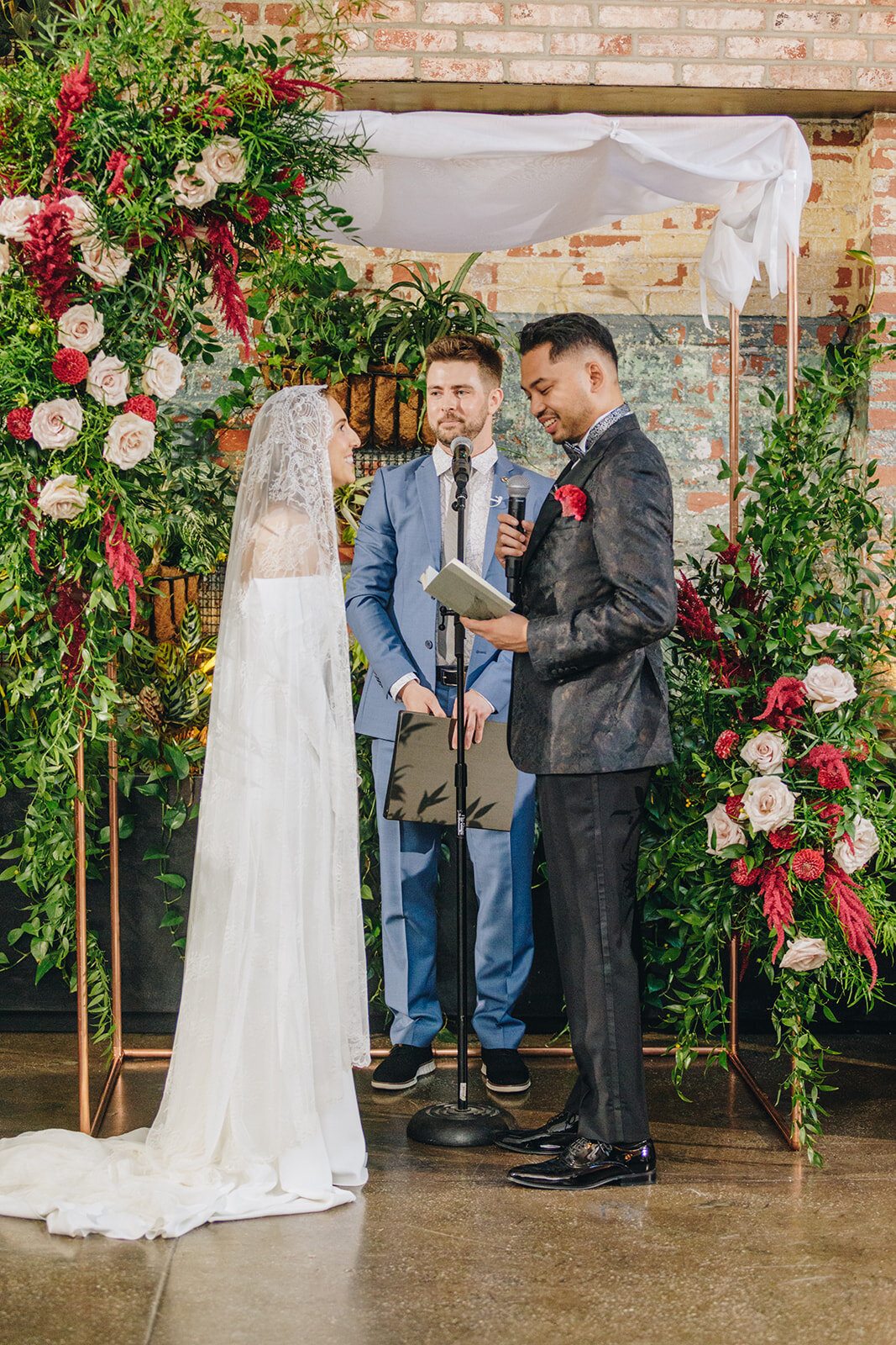 bride and groom at the alter, under a flower arch