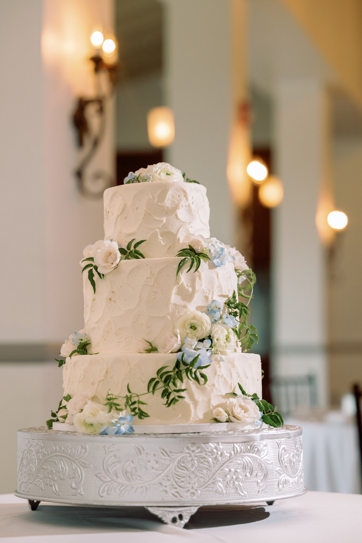 Cream wedding cake with blue  and white flowers