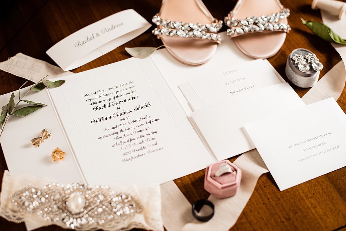 Detail photo of brides shoes, jewelry and wedding invitation