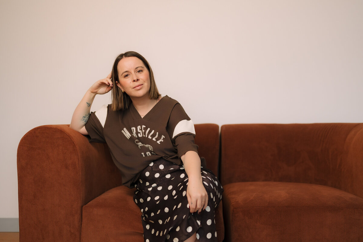 Liv Rollings posing on rust colored couch