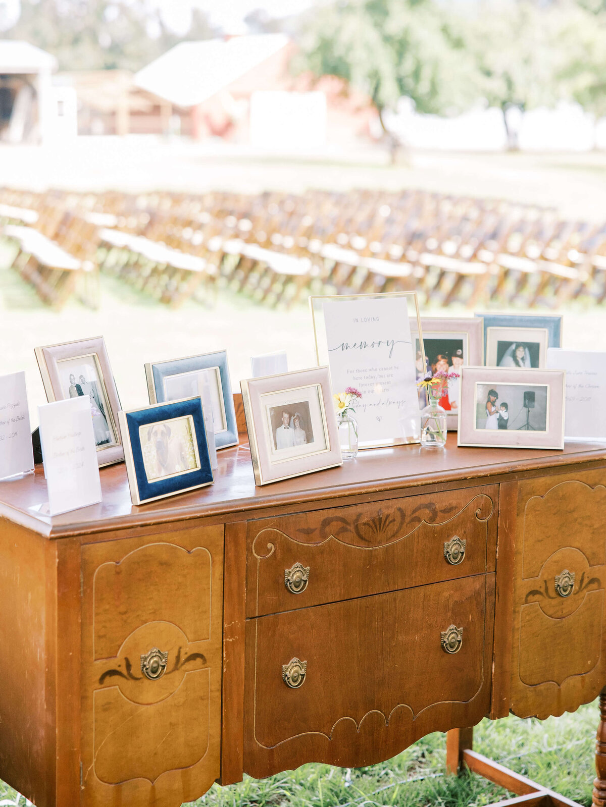 Framed pictures sit on top of a decorative cabinet, representing wedding rental items from Birdie June Events.