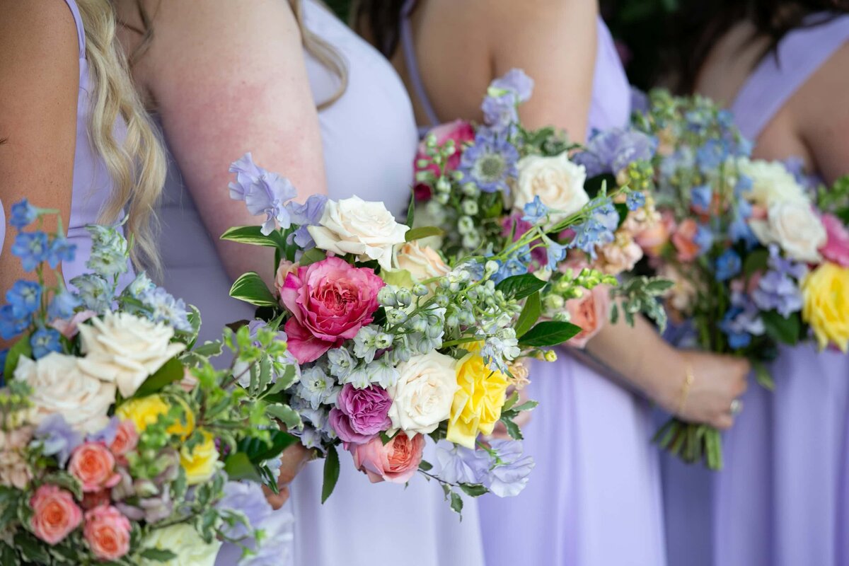 colorful spring bridesmaids bouquets against lilac bridesmaids dresses