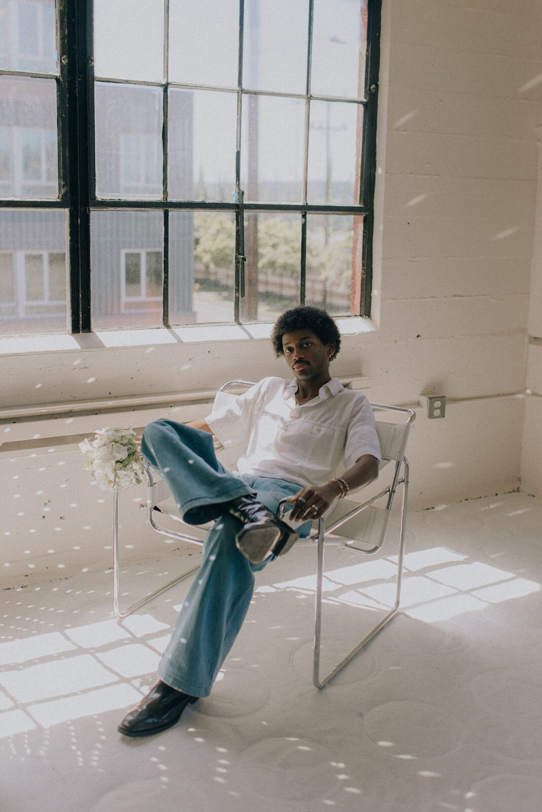 Man sitting in a chair with disco ball light reflecting at Aqui Studio