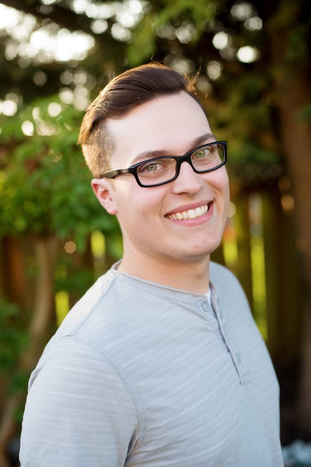 Young man with glasses smiles while outside!